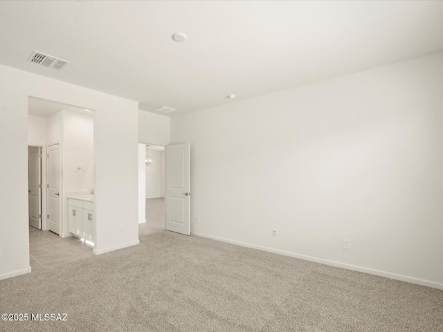 empty room with baseboards, visible vents, and light carpet