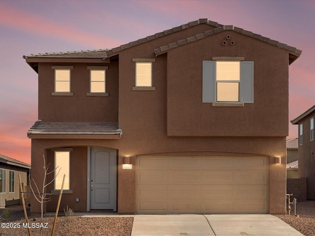 view of front of property featuring stucco siding, an attached garage, and driveway