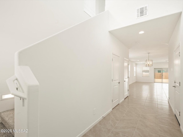 corridor featuring light tile patterned floors, baseboards, visible vents, recessed lighting, and a chandelier