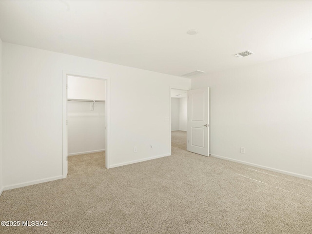 unfurnished bedroom featuring a spacious closet, visible vents, carpet flooring, and baseboards