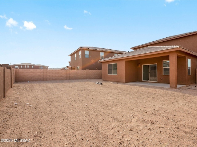 rear view of house with stucco siding, a fenced backyard, and a patio area