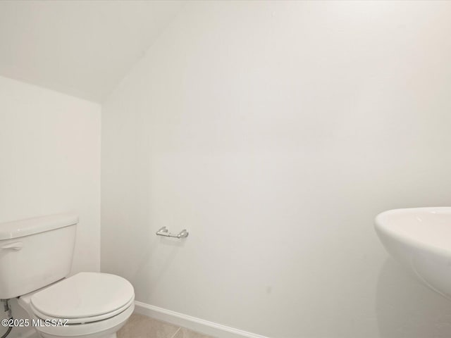 bathroom with a sink, baseboards, toilet, and tile patterned flooring