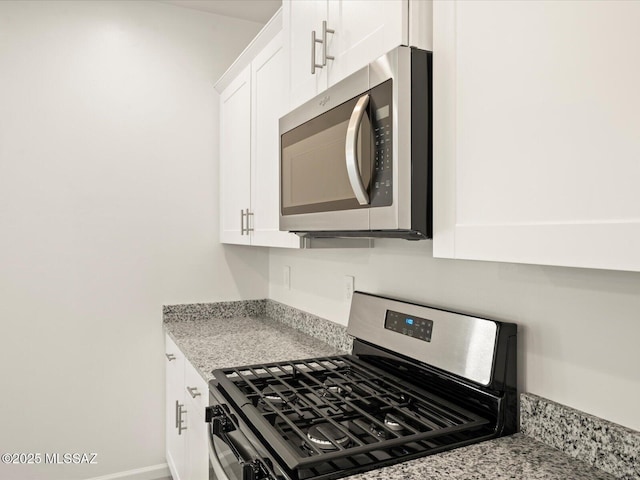 kitchen with light stone counters, appliances with stainless steel finishes, and white cabinetry