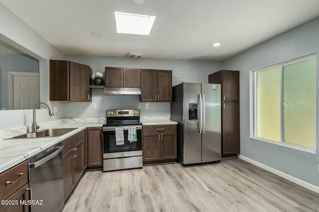 kitchen featuring dark brown cabinetry, sink, a skylight, light hardwood / wood-style flooring, and stainless steel appliances