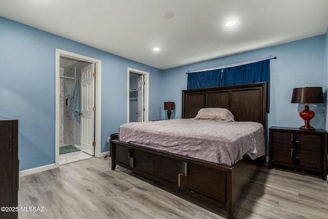 bedroom with a closet, a spacious closet, ensuite bath, and light hardwood / wood-style flooring