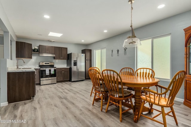 dining space with a skylight, light hardwood / wood-style floors, and sink