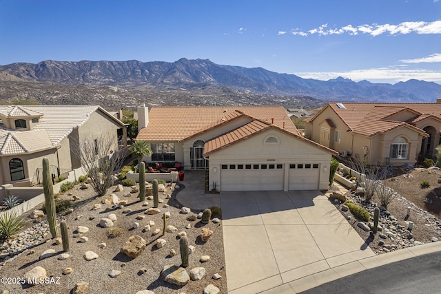 view of front of house featuring driveway, a tiled roof, an attached garage, a mountain view, and stucco siding