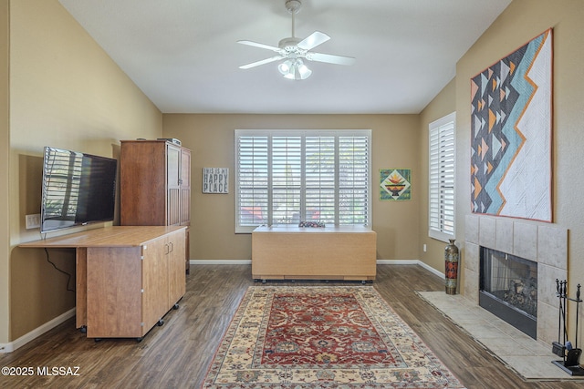 office with ceiling fan, a tiled fireplace, vaulted ceiling, and wood finished floors