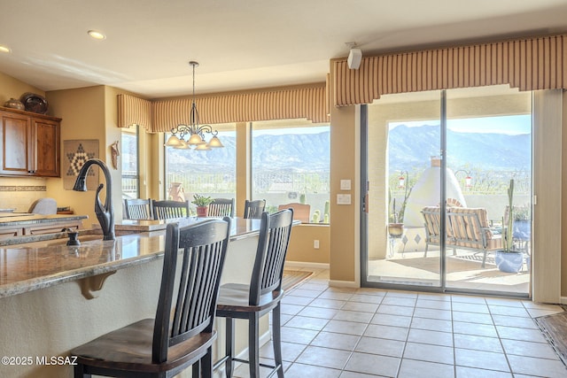 dining area featuring light tile patterned floors, recessed lighting, a mountain view, a chandelier, and baseboards