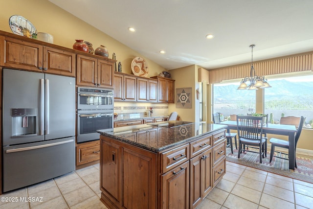 kitchen with brown cabinets, stainless steel appliances, vaulted ceiling, a kitchen island, and dark stone countertops