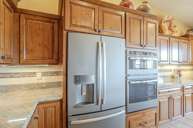 kitchen featuring appliances with stainless steel finishes, brown cabinetry, and backsplash