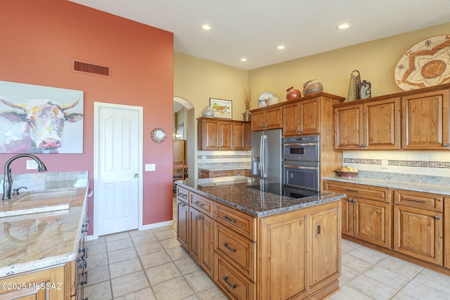 kitchen with arched walkways, visible vents, appliances with stainless steel finishes, a sink, and a kitchen island