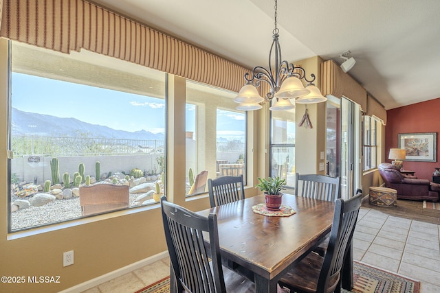 dining room with lofted ceiling, a chandelier, light tile patterned flooring, a mountain view, and baseboards