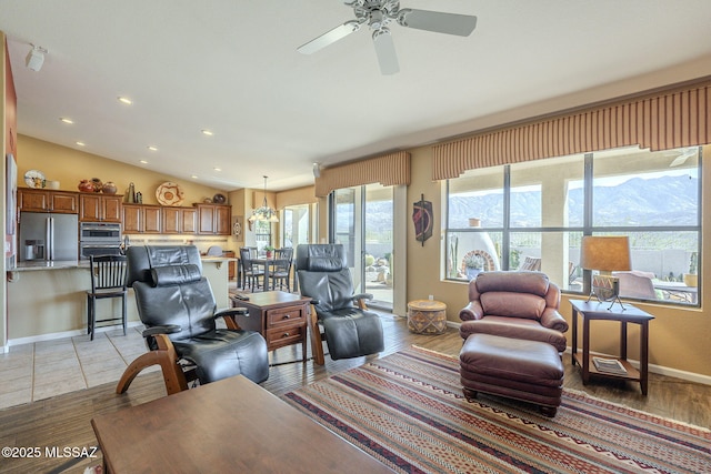 living area featuring lofted ceiling, recessed lighting, a ceiling fan, light wood-type flooring, and baseboards