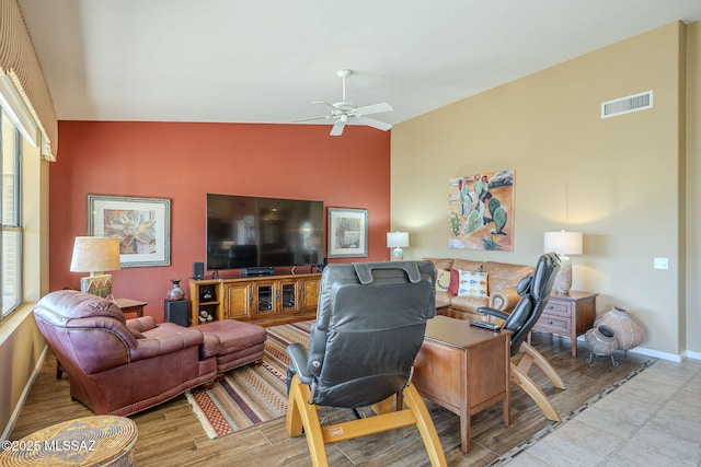 living room featuring baseboards, visible vents, a ceiling fan, lofted ceiling, and light wood-style flooring