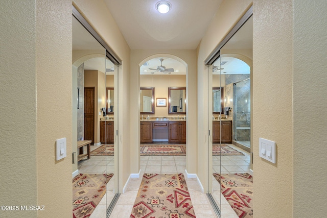 interior space featuring arched walkways, a textured wall, a sink, and light tile patterned floors