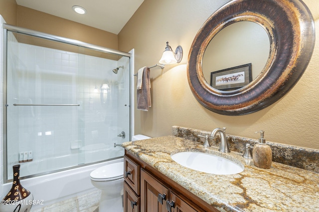 full bathroom featuring toilet, combined bath / shower with glass door, and vanity