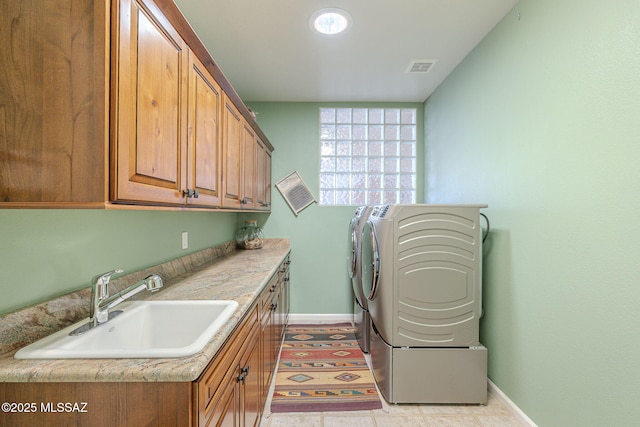 laundry area featuring cabinet space, a sink, washer and clothes dryer, and baseboards