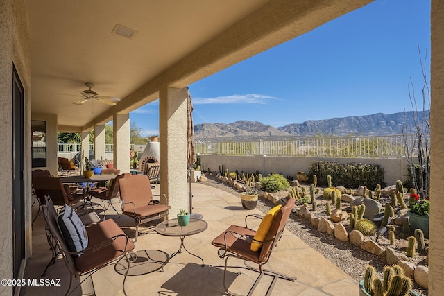 view of patio / terrace with outdoor dining area, a fenced backyard, a mountain view, and ceiling fan