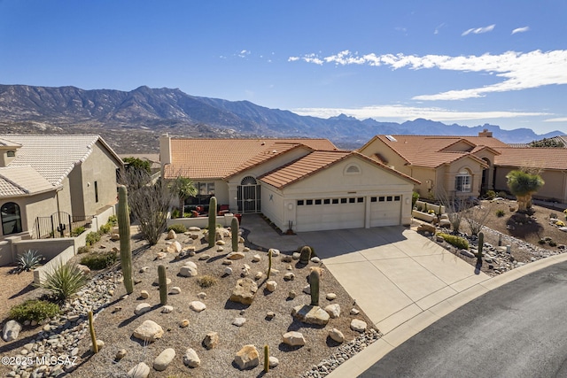 view of front of home featuring concrete driveway, an attached garage, a mountain view, fence, and a tiled roof