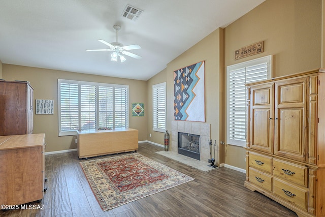 interior space with visible vents, a ceiling fan, vaulted ceiling, wood finished floors, and a tile fireplace