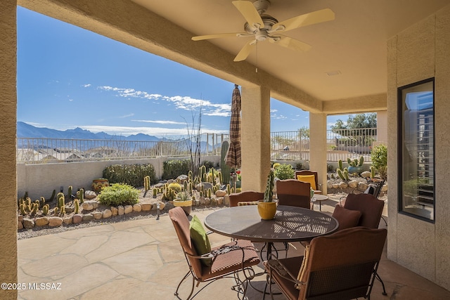 view of patio / terrace with a fenced backyard, a mountain view, outdoor dining area, and a ceiling fan