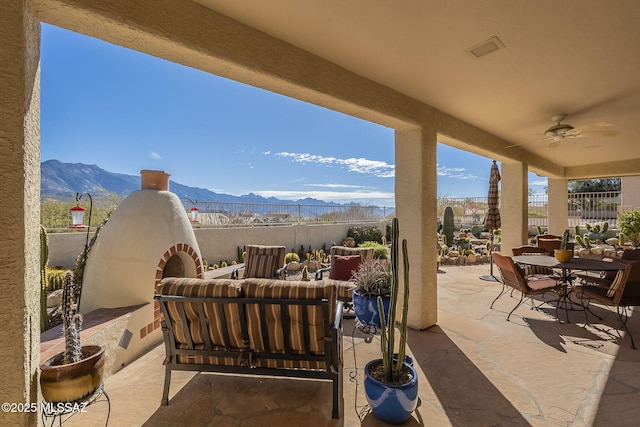 view of patio featuring ceiling fan, outdoor dining area, a mountain view, outdoor lounge area, and fence