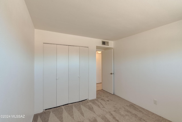 unfurnished bedroom featuring light carpet and a closet