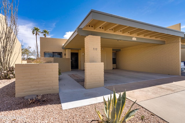 view of front of home featuring driveway, an attached carport, and brick siding