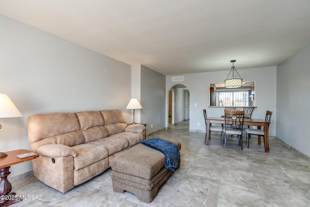 living room with arched walkways, visible vents, and baseboards