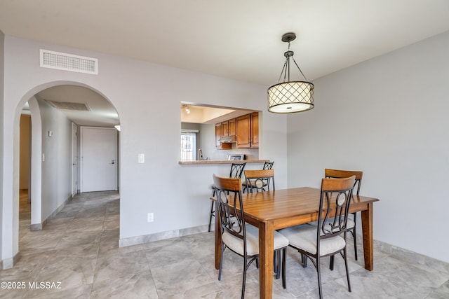 dining room with arched walkways, visible vents, and baseboards