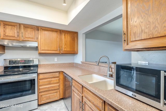 kitchen featuring stainless steel appliances, brown cabinetry, a sink, and under cabinet range hood