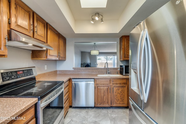 kitchen featuring brown cabinets, stainless steel appliances, light countertops, under cabinet range hood, and a sink