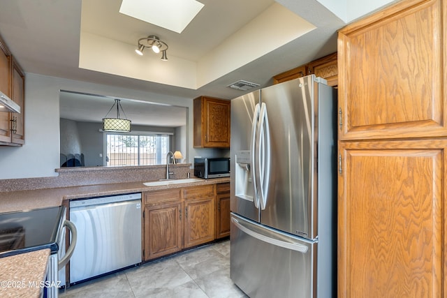 kitchen featuring visible vents, a raised ceiling, appliances with stainless steel finishes, light countertops, and a sink