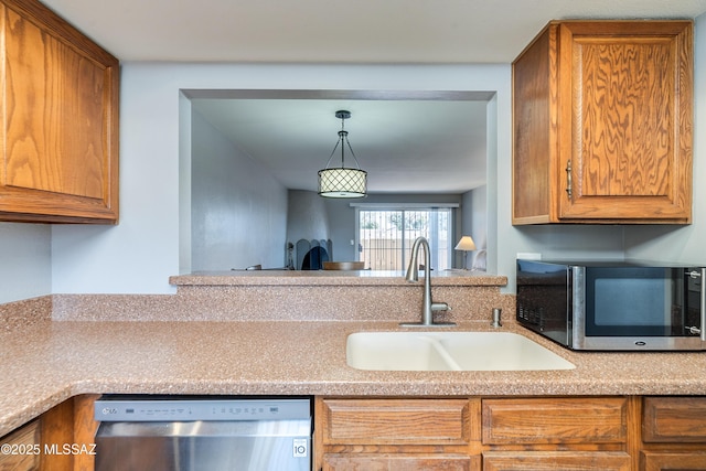 kitchen featuring light countertops, hanging light fixtures, appliances with stainless steel finishes, brown cabinetry, and a sink