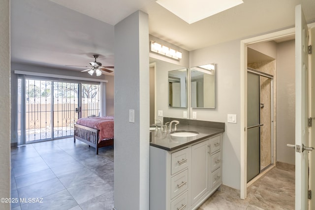 ensuite bathroom featuring a skylight, vanity, a ceiling fan, a stall shower, and ensuite bath