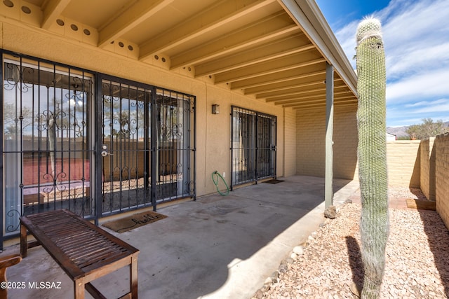 view of exterior entry featuring a patio area, fence, a chimney, and stucco siding