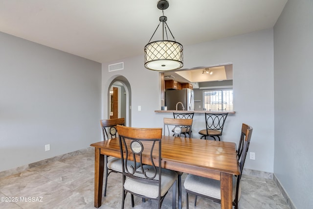 dining area with arched walkways, visible vents, and baseboards