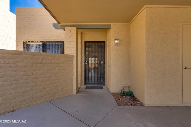 doorway to property featuring fence and stucco siding