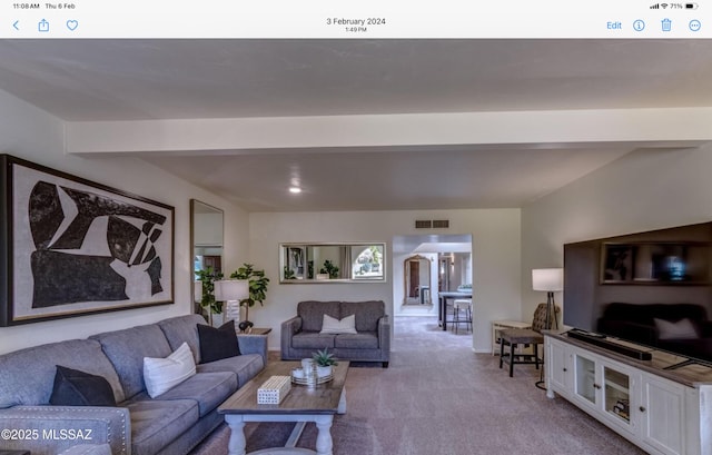 carpeted living room featuring beam ceiling