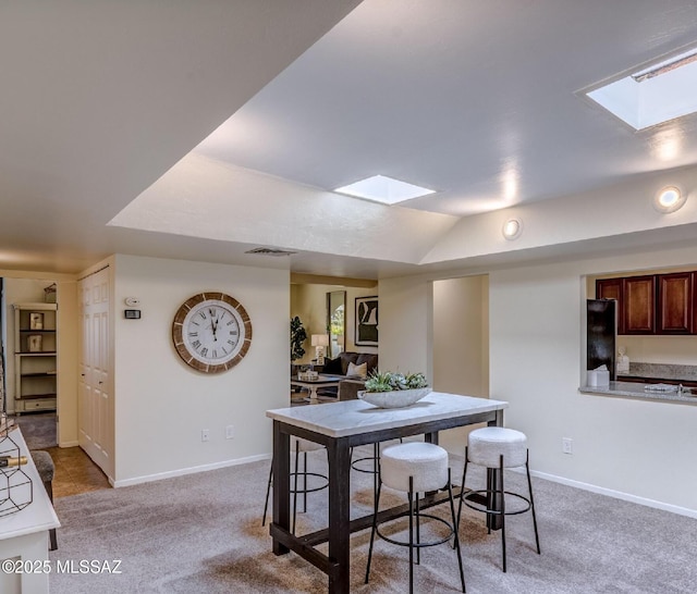 dining space with carpet floors and vaulted ceiling with skylight