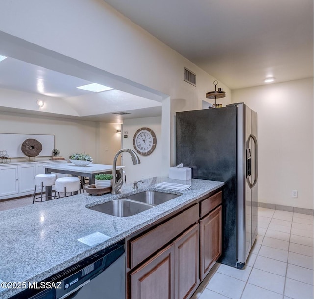 kitchen with stainless steel appliances, light stone countertops, sink, and light tile patterned floors