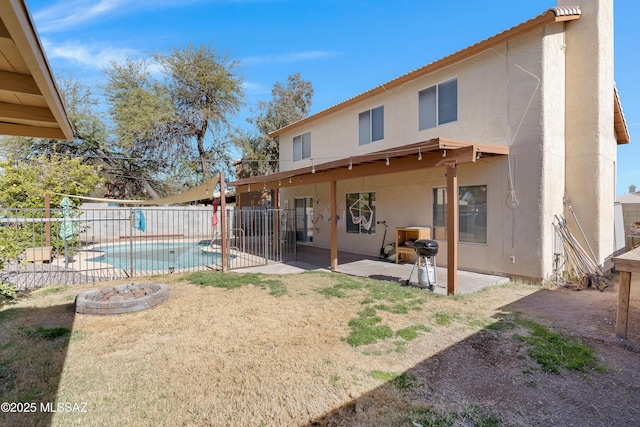 back of property with a fenced in pool and a patio