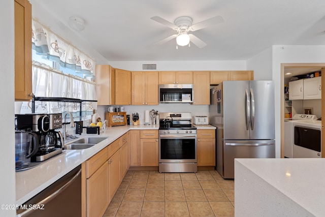 kitchen featuring sink, light tile patterned floors, light brown cabinets, appliances with stainless steel finishes, and washing machine and dryer