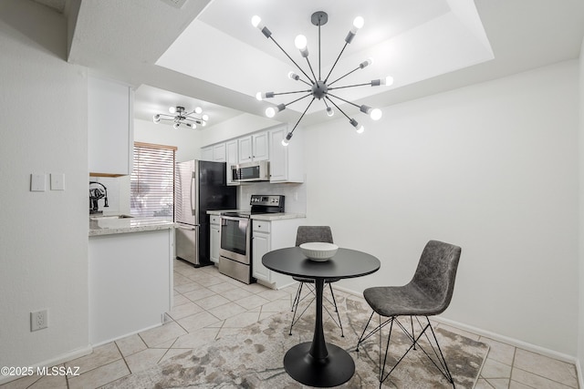 kitchen featuring appliances with stainless steel finishes, tasteful backsplash, sink, white cabinets, and an inviting chandelier