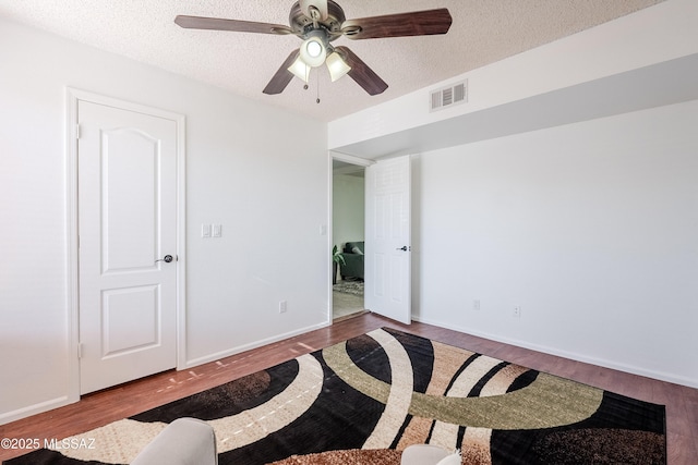 empty room with wood-type flooring, ceiling fan, and a textured ceiling