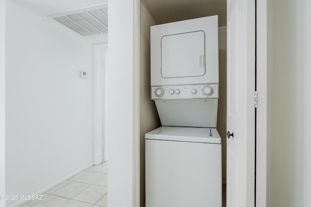 laundry room featuring light tile patterned floors and stacked washer and clothes dryer