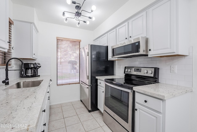 kitchen featuring sink, light stone counters, light tile patterned floors, appliances with stainless steel finishes, and white cabinets