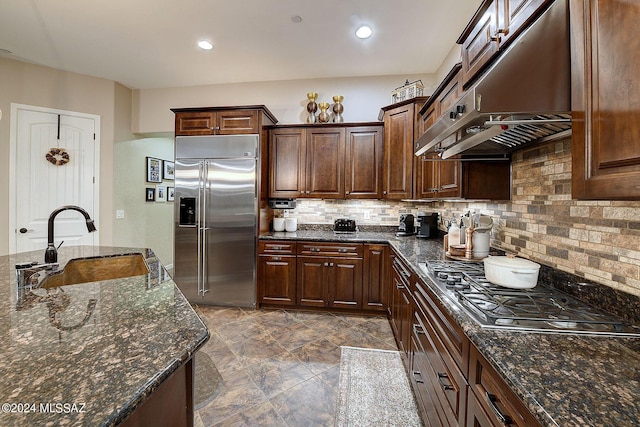 kitchen featuring dark brown cabinetry, sink, dark stone countertops, stainless steel appliances, and backsplash