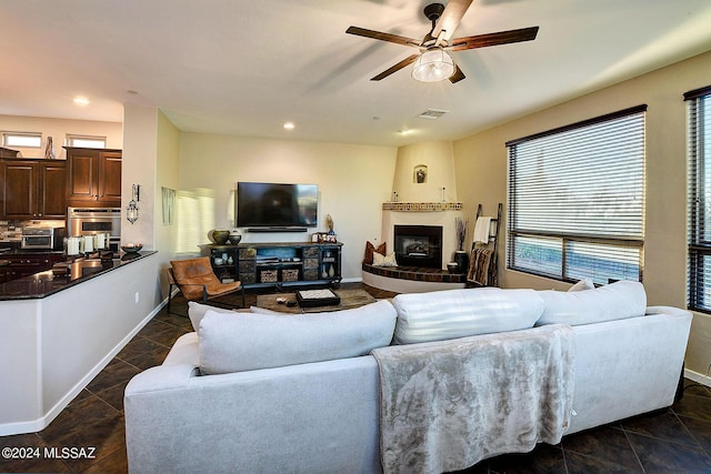 living room with ceiling fan, dark tile patterned flooring, and a fireplace